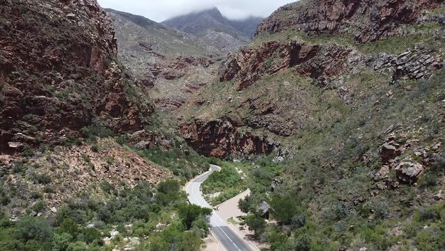 Epic aerial shot travelling through the scenic mountainous landscape which surrounds the Meiringspoort pass, the road below connects the Klein Karoo with the Groot Karoo, South Africa