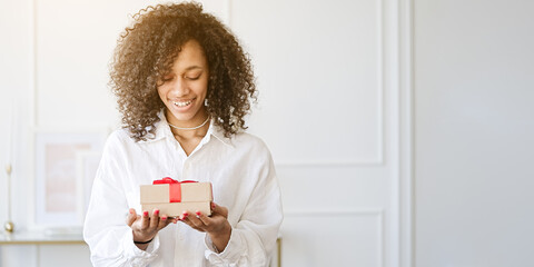 Excited african American young woman unpack gift box, overjoyed girl feel euphoric open shipped package parcel from delivery service                               