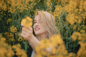 Uśmiechnięta dziewczyna z kwiatem w ręce na polu