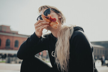 Dziewczyna w okularach jedząca Pizzę na dworzu - obrazy, fototapety, plakaty