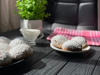 Round cookies on a white plate. Sunlight from the window. White dishes on a black background.