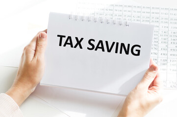 tax savings inscription on the notebook, which is held in the hands of a businessman against the background of the desktop