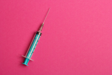 Medical syringe on a pink background. A syringe for injection. The concept of health and beauty