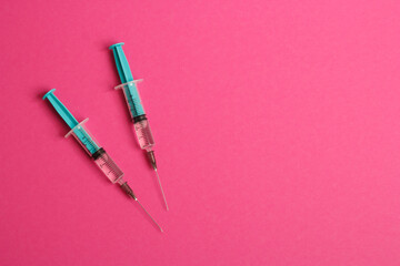 Medical syringe on a pink background. A syringe for injection. The concept of health and beauty