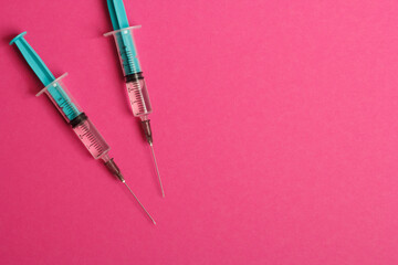 Medical syringe on a pink background. A syringe for injection. The concept of health and beauty