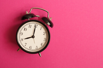 black vintage style alarm clock isolated on a pink background