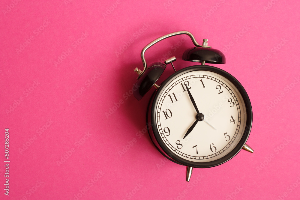 Poster black vintage style alarm clock isolated on a pink background