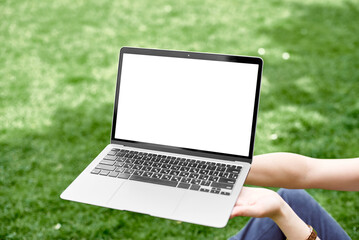 Computer screen blank mockup. Mockup of a laptop in the background of the lawn. Close-up of a laptop with a blank screen on the background of grass. Banner. The concept of work in the open air.