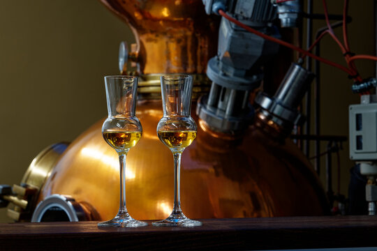 Liqueur glasses in front of a gin distiller.