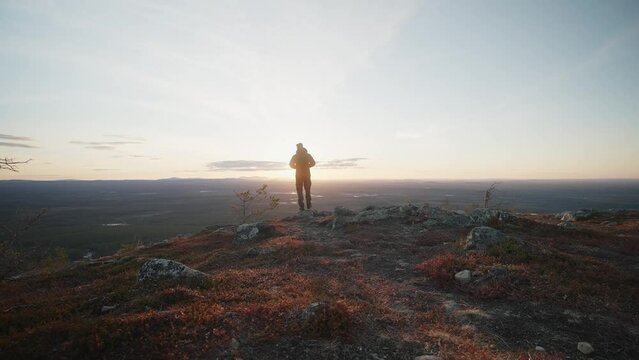Man walking into sunset ontop of a fell in Lapland during spring.