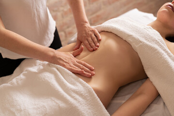 Fototapeta na wymiar Top view, hands massaging female abdomen.Therapist applying pressure on belly, beauty treatments. Woman receiving massage at spa salon