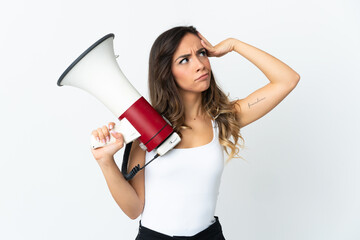 Young caucasian woman isolated on white background holding a megaphone and having doubts