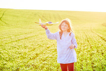 Sincere emotions. Happy little girl running on the field with yellow toy plane in their hands.