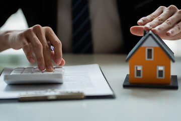 A real estate agent or bank officer explains the interest on the loan to the customer with a home purchase contract or insurance in the home office.