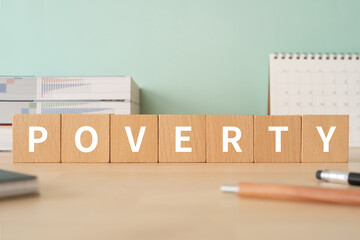貧乏・貧困のイメージ｜「POVERTY」と書かれた積み木が置かれたデスク