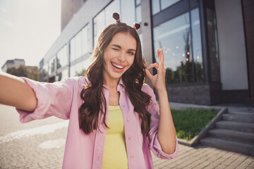 Self-portrait of attractive cheerful wavy-haired girl traveling showing ok-sign winking having fun...