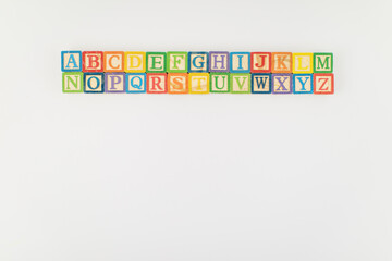 An arrangement of children painted alphabet wooden blocks isolated with white background for text...
