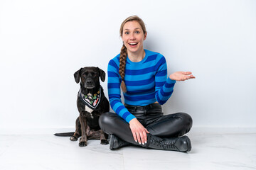 Young caucasian woman sitting on the floor with his puppy isolated on white background with shocked...