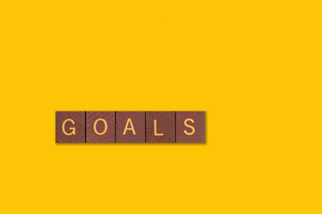 Wood blocks with the word goals on a bright yellow background