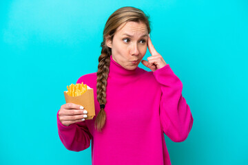 Young caucasian woman holding fried chips isolated on blue background having doubts and thinking