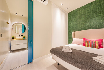 Corner of a bedroom with striking decoration next to an entrance to a bathroom with a white chest of drawers