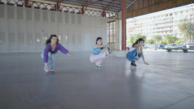 Three girls hold feet while roller skating fast forward, follow shot