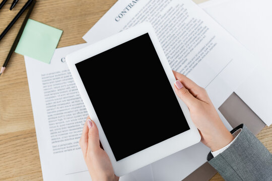 cropped view of woman holding digital tablet with blank screen above papers with contract.