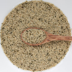 Hemp seeds in a wooden spoon in a circle-shaped seed background, top view with copy space