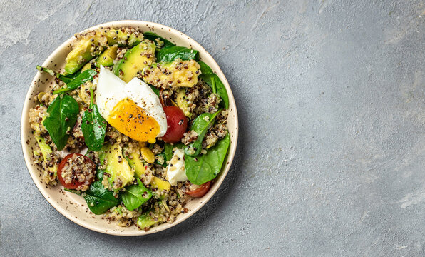Quinoa buddha bowl with avocado, egg, tomatoes, spinach and sunflower seeds on a light background. Homemade food. Healthy, clean eating. Vegan or gluten free diet, Long banner format. top view