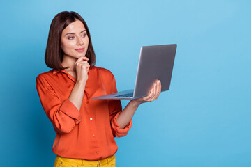 Portrait of attractive focused minded skilled girl using laptop thinking isolated over bright blue...