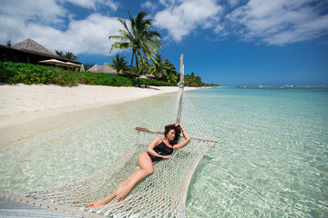 Woman in hammock on tropical beach at island