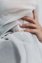 Portrait of young female covered with light fabric and hand on neck. Self care concept. Social...