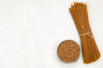 brown spaghetti and buckwheat in cup on gray background with copy space