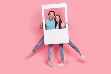 Full body photo of two cheerful excited carefree people look camera album card isolated on pink...