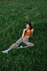 A woman lies on fresh spring green grass in a park without mosquitoes or ticks and enjoys relaxing while watching the sunset. The concept of safe outdoor recreation