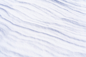 Fototapeta na wymiar Freshly fallen snow surface looking like dunes shaped by wind. Winter abstract snow texture background.