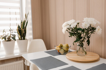 Stylish kitchen interior with dining table and chairs. Home design. Scandinavian trendy interior. Ficus in a flower pot. Big window