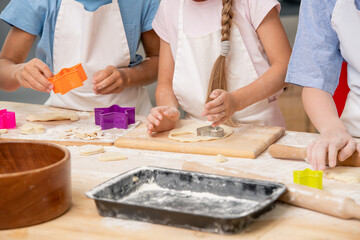 Little child sugar into bowl with shaked raw eggs while helping his mom with dough for homemade pastry by table in the kitchen