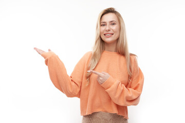 Attractive blonde girl promoter holding something in hand demonstrating empty space with excited face isolated on white background