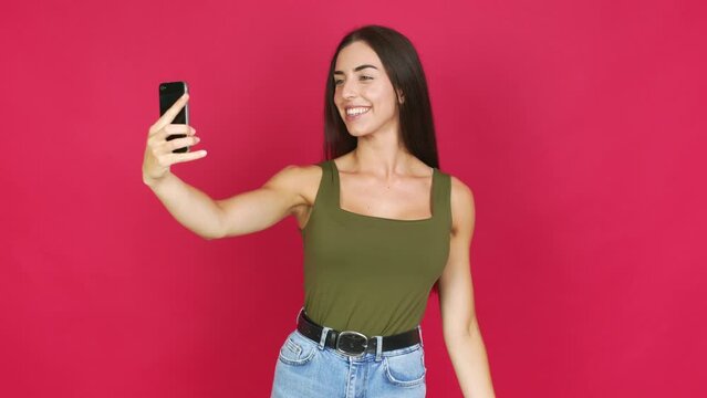 Young brunette woman using mobile phone and doing a selfie over isolated background