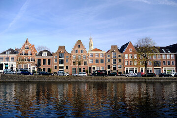 Fototapeta na wymiar Haarlem, Netherlands - April 12. 2022: Panoramic view of traditional Dutch houses lining the river Sparne in springtime.