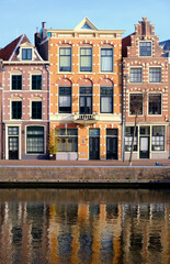 Fototapeta na wymiar Haarlem, Netherlands - April 12. 2022: Three traditional Dutch houses lining the river Sparne in springtime. Reflections in the water.
