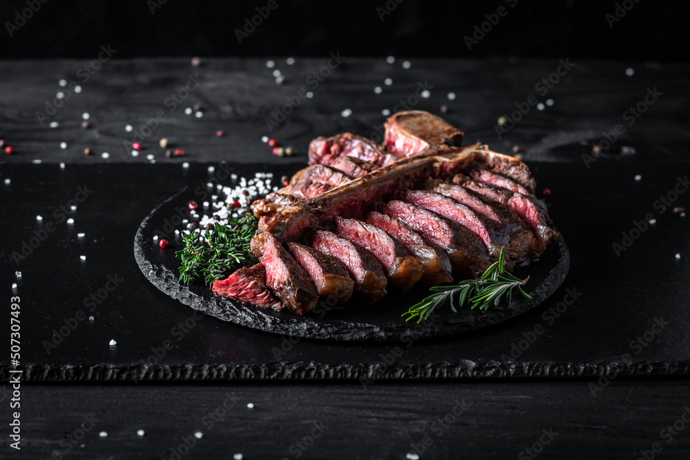 Wall mural juicy steak rare beef with spices on a wooden board and garnish of asparagus