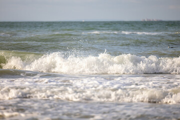 Crashing waves lapping on the sandy beach one after another under a blue sunset sky, selective focus used. High quality photo