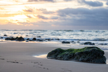 Soft colored dramatic sunset with dark clouds in the background with focus on a large rock at a slightly rocky coast in France, Cap Blanc-Nez. High quality photo