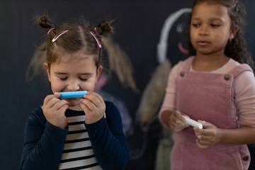 Group of little girls posing in front of blackboard wall paintings indoors in playroom.