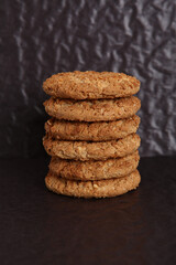 Oatmeal, fig, hazelnut, pistachio and sesame cookies on a black background. Enjoyable snack.