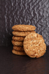 Oatmeal, fig, hazelnut, pistachio and sesame cookies on a black background. Enjoyable snack.