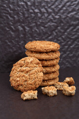 Oatmeal, fig, hazelnut, pistachio and sesame cookies on a black background. Enjoyable snack.