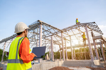 3 Workers in Construction Site, Architect or Engineer technician use a laptop watching team of Workers Steel roof structure under construction. Teamwork Concept. © tong2530